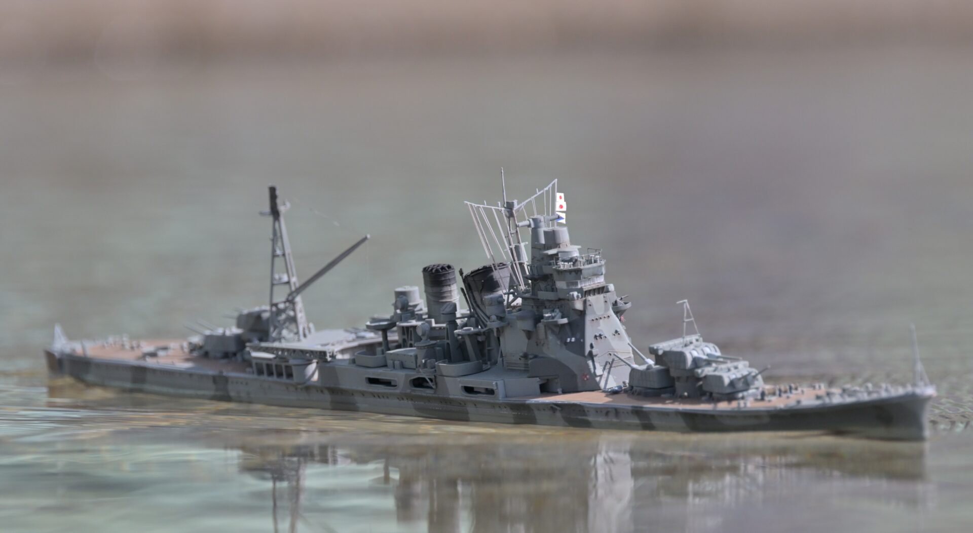 Remote-controlled 1/350 Takao heavy cruiser model creating a wake on Yamato Pond, recreated with Godzilla Minus One style camouflage.