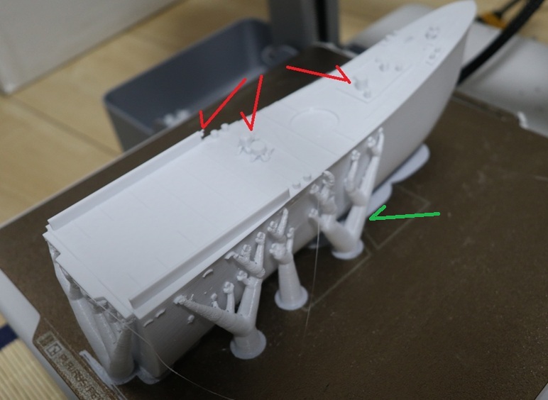 “FDM 3D-printed ship hull section on a Bambu Lab A1 with heavy supports; red arrows highlight fragile deck vents that snapped due to print orientation.”
