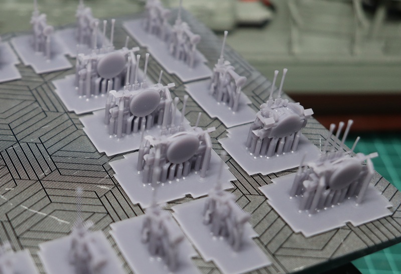 Resin 3D printed gun barrels on rafts with supports, oriented near-vertical to reduce support marks and keep thin parts straight.