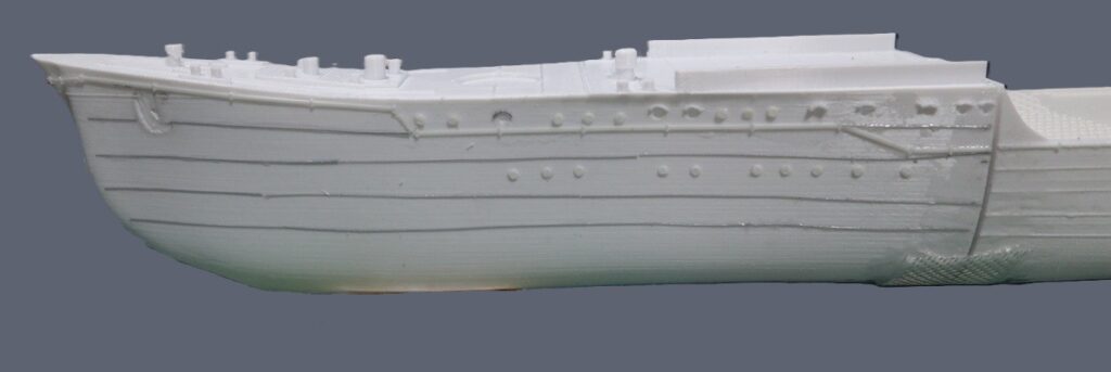 Post-print photo of the destroyer Yukikaze hull side (PETG), showing uneven window frames and external cable lines caused by inconsistent extrusion depth when extruding toward a tilted construction plane; some details become thinner or disappear.