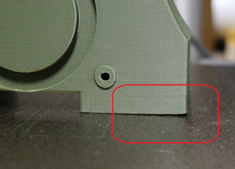 Close-up photo showing first-layer lifting (warping) on an FDM print, highlighted by a red circle, used for a Bambu Studio warping troubleshooting guide.