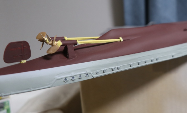 Close-up of a 1/150 IJN destroyer Yukikaze RC hull showing twin propeller shafts, propellers, and rudder area during drivetrain setup (shaft, stern tube, and steering linkage prep)