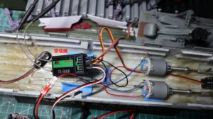 Top-down view inside a 1/150 Yukikaze RC hull showing twin motors, receiver, servo, and wiring layout during test setup