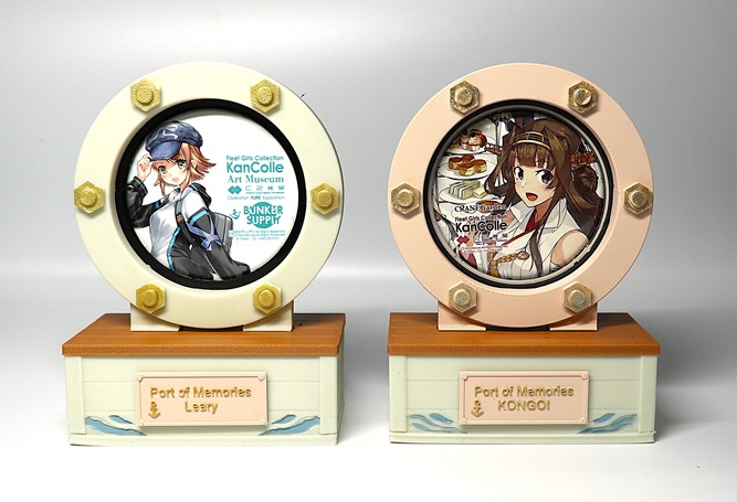 Two 3D printed 56mm can badge holders with porthole-style frames and display bases.